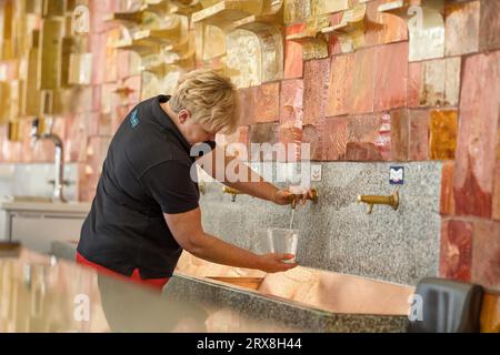 Femme remplissant des gobelets en plastique avec de l'eau minérale naturelle, Krynica-Zdroj, Pologne Banque D'Images