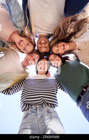 Groupe multiracial vertical jeunes gens heureux debout en cercle et souriant excités à la caméra. Banque D'Images