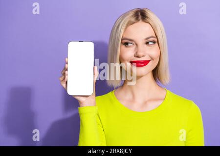 Photo de belle fille intelligente porter une chemise jaune élégant regarder le panneau Web dans l'écran tactile de smartphone isolé sur fond de couleur violette Banque D'Images