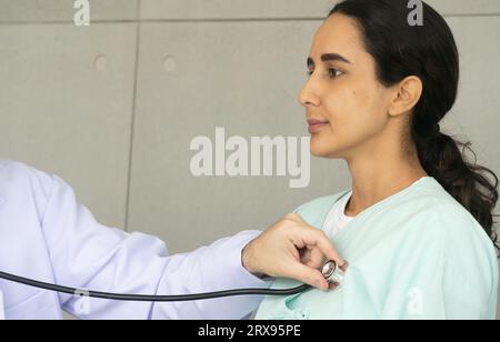 Diagnostic par stéthoscope d'un médecin caucasien de cause fondamentale chez une patiente hispanique. L'examen médical de santé et check-up avec t Banque D'Images