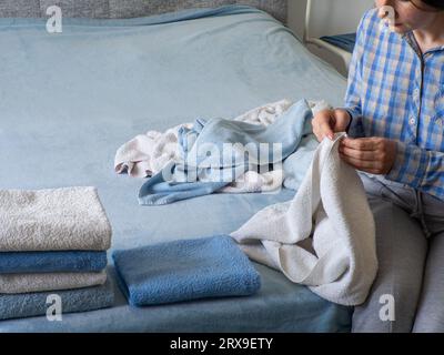 Lessive, mains et femme avec pile de serviettes pour le nettoyage de printemps  linge, tissu et textiles pour nettoyer dans le travail à la maison. Personne,  pile de lavage frais ou Photo