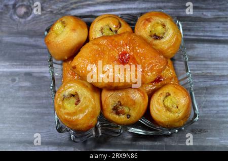 Fond de mini pâtisserie danoise farcie et garnie de sirop sucré au miel et de cerise et mini rouleau de bouffée tourbillon à la cannelle sucré avec ho Banque D'Images