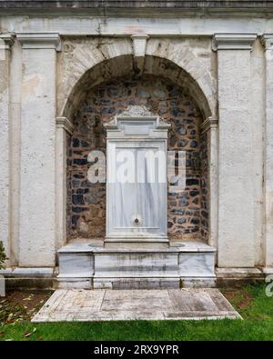 Une belle fontaine en marbre blanc située dans le jardin du Pavillon Mecidiye, Istanbul, Turquie. La fontaine est entourée d'un mur de pierre et présente des sculptures et des dessins complexes Banque D'Images