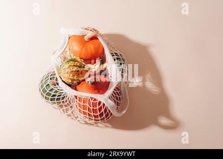 Citrouilles oranges dans un sac à cordes. Concept zéro déchet, alimentation saine. Ombres nettes, vue de dessus, mise à plat. Banque D'Images