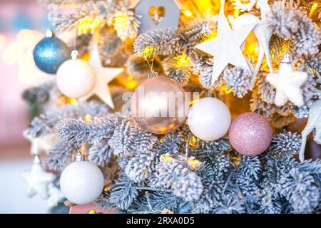 Sapin de Noël radieux habillé de magnifiques boules bleues et rosées, placé sur un fond étincelant Banque D'Images