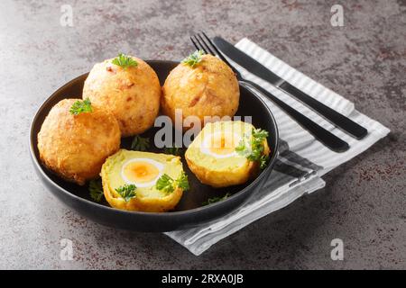 Délicieuses boules de pommes de terre farcies d'œuf à la coque, puis frites en gros plan dans une assiette sur la table. Horizontal Banque D'Images