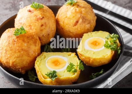 Boules de purée de pommes de terre farcies d'œuf à la coque puis frites en gros plan dans une assiette sur la table. Horizontal Banque D'Images