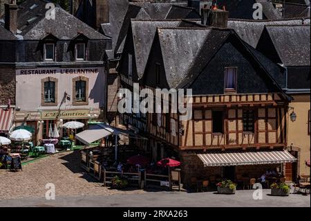 Assis à l'ombre aux tables extérieures des restaurants et des bars sur le quai de la place Saint-Sauveur dans le quartier Saint-Goustan d'Auray, une ville sur le Loch de la rivière en Bretagne Sud, France. Auray est une destination touristique populaire avec des bâtiments médiévaux bien restaurés, beaucoup à colombages. Banque D'Images