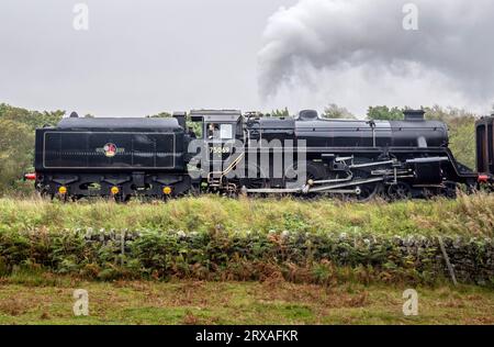 Un homme se penche vers la fenêtre de la locomotive no 75069 alors qu'elle traverse le North York Moors National Park pendant le North Yorkshire Moors Railway 50th Anniversary Steam Gala. Date de la photo : dimanche 24 septembre 2023. Banque D'Images