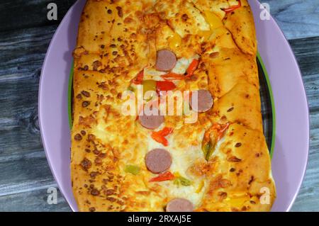 Fromage Fougasse recouvert de tranches de poivrons verts, de fromage et de saucisses coupées cuites au four, le pain de fougasse est un type de pain typiquement associé Banque D'Images