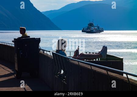 Fodness, Norvège, 24 juin 2023 : silhouette d'une femme sur un téléphone intelligent attendant le ferry Fodnes-Mannheller pendant une soirée d'été. Il y en a 18 Banque D'Images