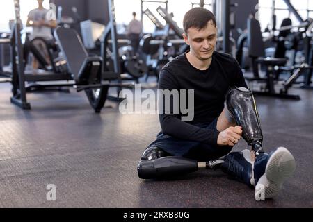 agréable jeune sportif mettant sur la jambe artificielle avant, entraînement, préparation à l'entraînement. gros plan. espace de copie. Banque D'Images