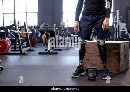 cliché recadré du corps d'un homme handicapé avec prothèse de jambe debout dans un gymnase moderne préparant à l'entraînement aux poids. espace de copie, arrière-plan flou. strengt Banque D'Images