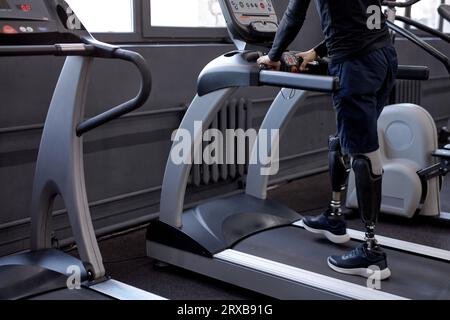 jambes artificielles courant sur tapis roulant. vue latérale recadrée. Santé mentale et motivation, Banque D'Images