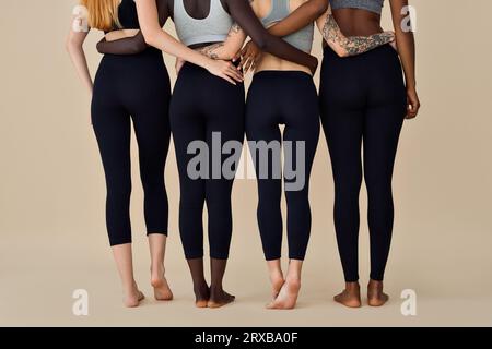 Jeunes femmes diverses portant des vêtements de sport debout sur fond beige. Banque D'Images