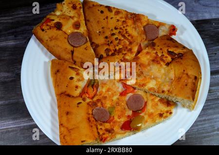 Fromage Fougasse recouvert de tranches de poivrons verts, de fromage et de saucisses coupées cuites au four, le pain de fougasse est un type de pain typiquement associé Banque D'Images