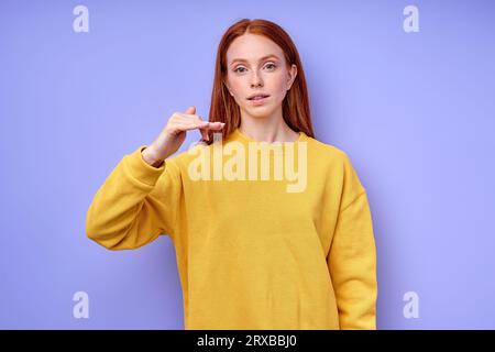 Belle rousse fille, professeur montrant la lettre F sur fond bleu. Alphabet de langue des signes. éducation gratuite pour les enfants sourds Banque D'Images