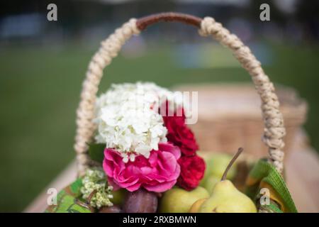Panier avec des fleurs. Fleurs et fruits. Panier en osier. Fleurs dans le jardin. Banque D'Images