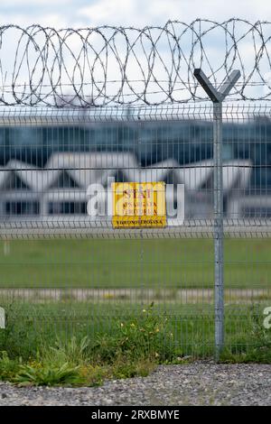 Marupe, Lettonie - 4 août 2023 - clôture du territoire de l'aéroport avec l'inscription de sécurité 'Stop, Secured Territory' et la Termin de l'aéroport de Riga Banque D'Images