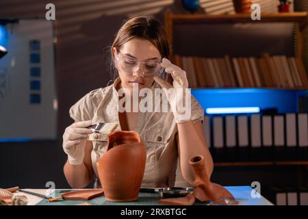 Belle archéologue féminine travaillant tard la nuit dans le bureau. Banque D'Images