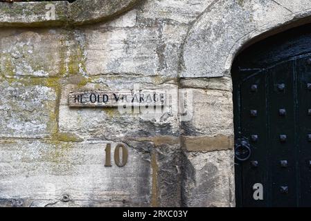 Un signe patiné pour le Old Vicarage sur un mur de pierre Burford High Street, Oxfordshire Angleterre Royaume-Uni Banque D'Images