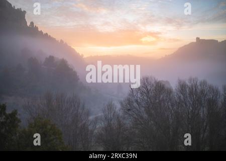 Paysage brumeux à l'aube autour des Chorreras del Río Cabriel à Enguídanos, Cuenca, Espagne avec son château au sommet de la montagne Banque D'Images