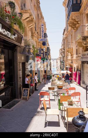 La Valette, Malte - 17 juin 2023 : rue avec bâtiment et tables de café dans les restaurants de la Valette, Malte. Banque D'Images