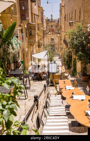 La Valette, Malte - 17 juin 2023 : escalier avec bâtiment et parasols avec tables de café dans les restaurants de la Valette, Malte. Banque D'Images