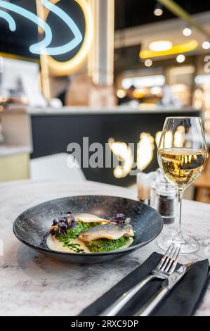 Bar en sauce crème avec épinards et huile verte sur une assiette blanche Banque D'Images