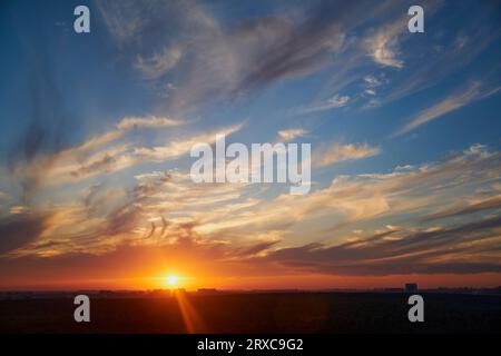 Le ciel d'été est embrasé par un coucher de soleil rouge vibrant, créant un paysage pittoresque qui met en valeur la beauté de la ville et de ses environs. Banque D'Images