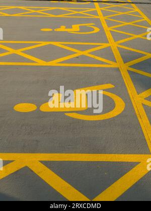 Deux places de stationnement pour handicapés fraîchement peintes en peinture jaune avec hachures croisées et symbole pour handicapés dans le parking, Angleterre, Royaume-Uni Banque D'Images