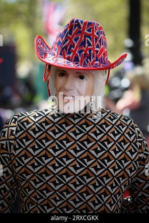 Un masque de reine Camilla porté sur le dos de la tête avec un chapeau Union Jack lors des célébrations du couronnement à London on the Mall. Banque D'Images