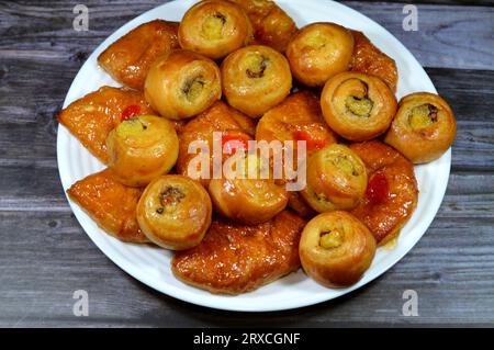 Fond de mini pâtisserie danoise farcie et garnie de sirop sucré au miel et de cerise et mini rouleau de bouffée tourbillon à la cannelle sucré avec ho Banque D'Images