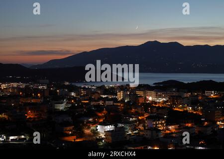 Vue nocturne de la ville de Ksamil en Albanie sur le fond de l'île de Corfou et la lune. Incroyable Riviera albanaise Banque D'Images