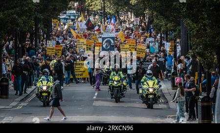 Police à moto devant les foules qui défilent à travers Londres pour protester contre ULEZ et son expansion. Banque D'Images