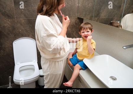 Maman et bébé se brossent les dents. Enfant âgé de deux ans (garçon de deux ans)mère et enfant s'amusant dans la salle de bain. Banque D'Images