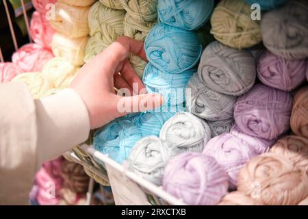 Main de femme choisissant le fil de laine coloré pour tricoter dans la boutique Banque D'Images