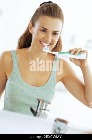 Happy young woman se brosser les dents dans la salle de bains Banque D'Images