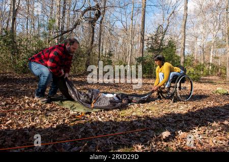 Un couple monte une tente sur un terrain de camping. Les deux sont handicapés mais adorent le plein air. Banque D'Images