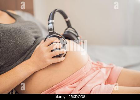 Mélodies dans l'utérus : écouteurs placés sur un ventre enceinte, liaison par la musique, une connexion réconfortante entre mère et bébé Banque D'Images