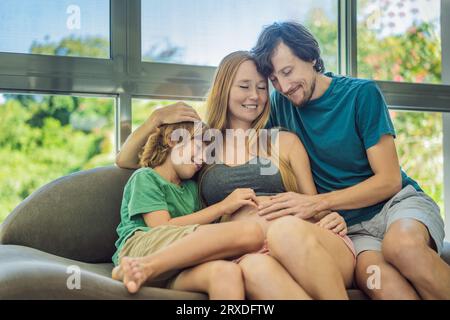 Les futurs parents, maman, papa et leur fils aîné partagent un moment réconfortant sur le canapé, discutant du voyage passionnant de la grossesse Banque D'Images