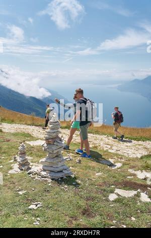 Pierres empilées par les touristes et quelques randonneurs sur le sommet de la montagne du Monte Baldo au lac de Garde près de Malcesine en Italie Banque D'Images