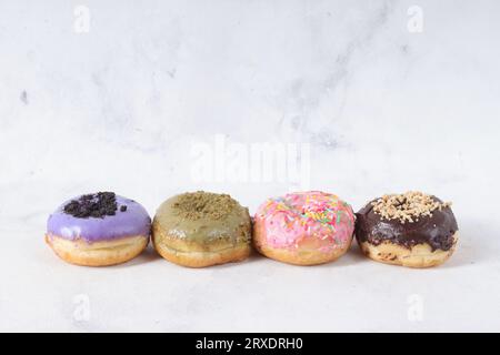 Délicieux beignets sucrés avec différentes saveurs sur une table. Image isolée sur fond blanc Banque D'Images