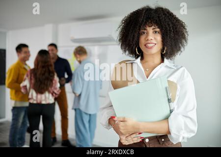 Portrait d'une femme joyeuse PDG d'une société INFORMATIQUE détenant un dossier de documents Banque D'Images