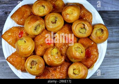 Fond de mini pâtisserie danoise farcie et garnie de sirop sucré au miel et de cerise et mini rouleau de bouffée tourbillon à la cannelle sucré avec ho Banque D'Images