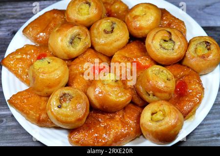 Fond de mini pâtisserie danoise farcie et garnie de sirop sucré au miel et de cerise et mini rouleau de bouffée tourbillon à la cannelle sucré avec ho Banque D'Images