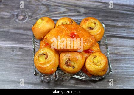 Fond de mini pâtisserie danoise farcie et garnie de sirop sucré au miel et de cerise et mini rouleau de bouffée tourbillon à la cannelle sucré avec ho Banque D'Images