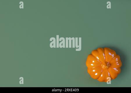 Fond d'Halloween avec citrouille orange. Design de vacances moderne. Bordure de fête d'Halloween sur fond de couleur naturelle vert olive. Pose à plat, vue de dessus, co Banque D'Images