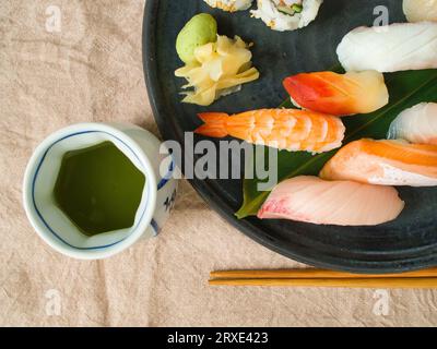 Plateau plat de sushi japonais coloré et de thé vert. Banque D'Images