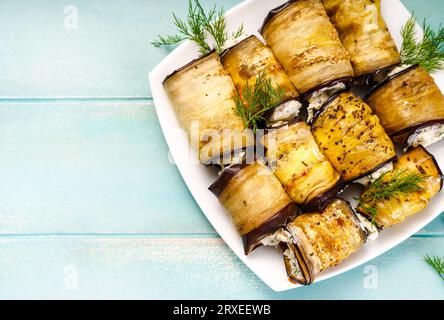 Apéritif d'aubergine avec fromage à la crème sur une assiette blanche. Apéritif Keto d'aubergines cuites au four sur un fond en bois bleu. Régime céto. Vue de dessus. Banque D'Images